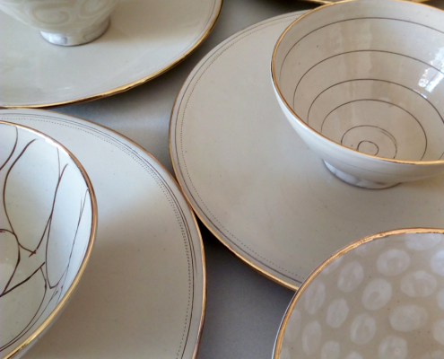 verschieden dekorierte Schälchen auf Tellern in Weiß/ Beigetönen der Keramikerin Uta Minnich